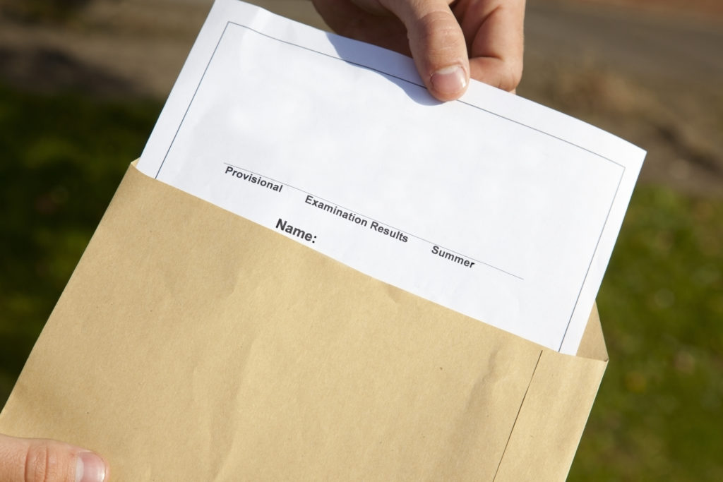 human hand removing exam results from brown envelope