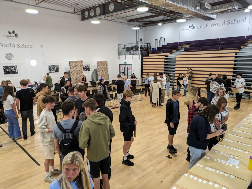 A photo showing students collecting their GCSE results on results day in the main hall of the academy building.