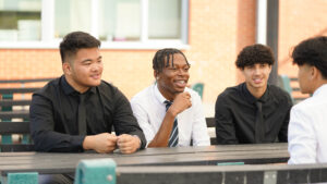 3 students at a table smiling