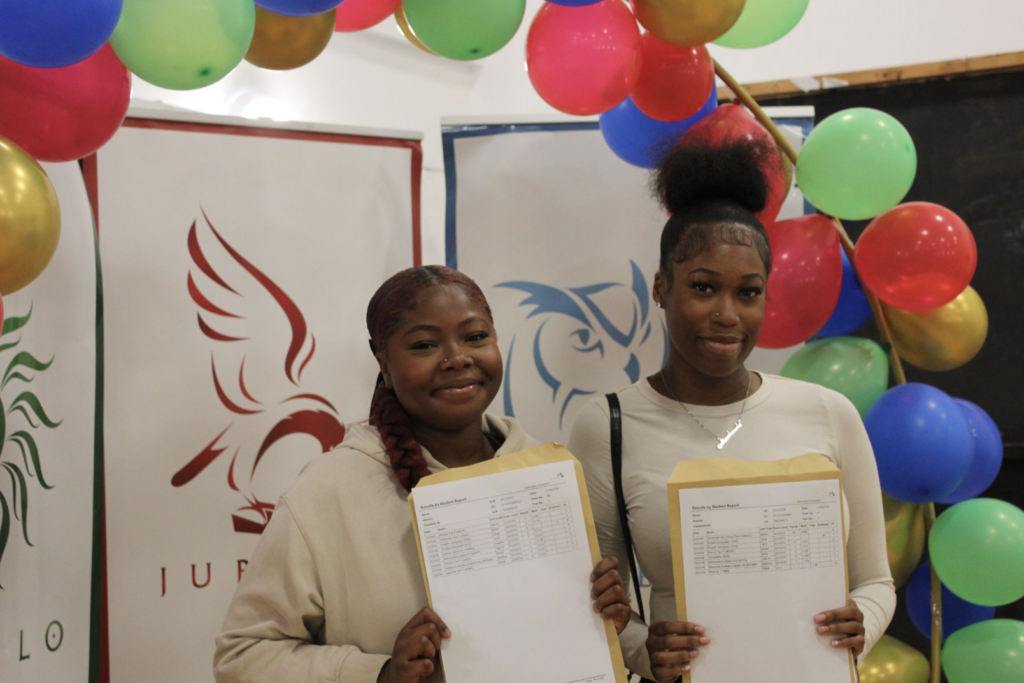 Students holding their results in front of a banner