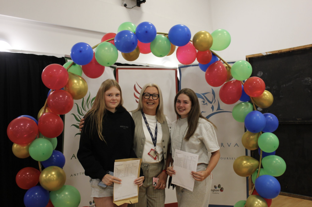 Students holding their results in front of a banner