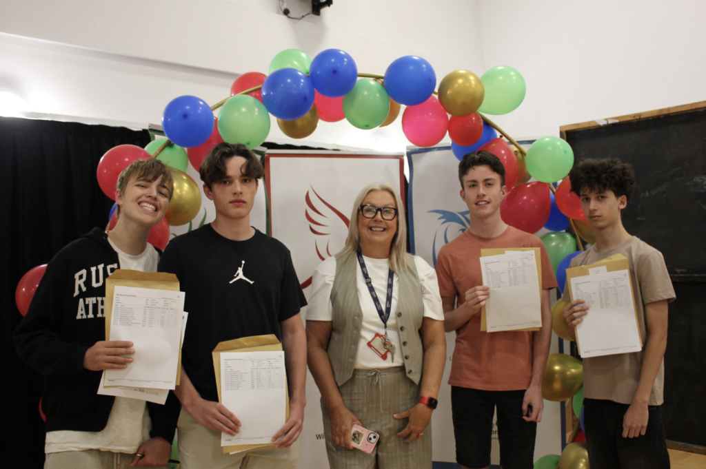 Students holding their results in front of a banner